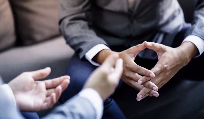 Two business professionals sitting across from each other, discussing at a desk.