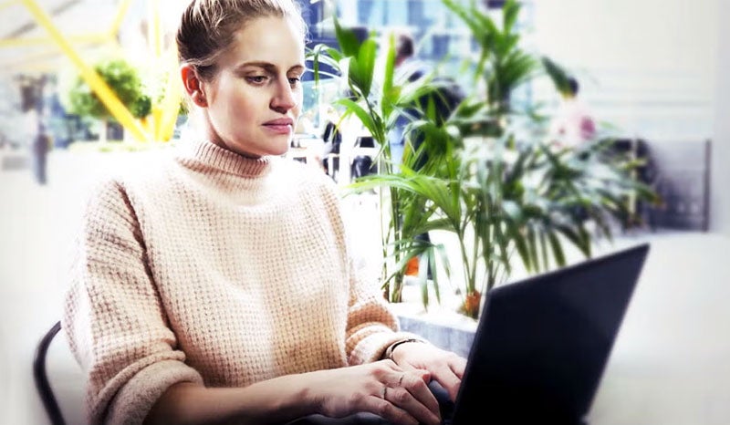 A woman focused on her laptop while working in a cozy coffee shop.