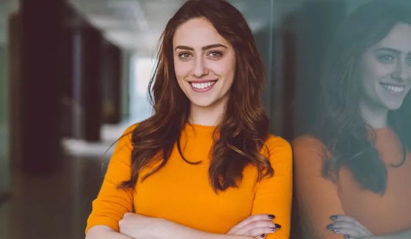 A smiling businesswoman confidently posing in a modern office.